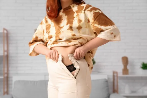 Image of woman trying to do her trousers up after pregnancy weight gain Malvern Wells