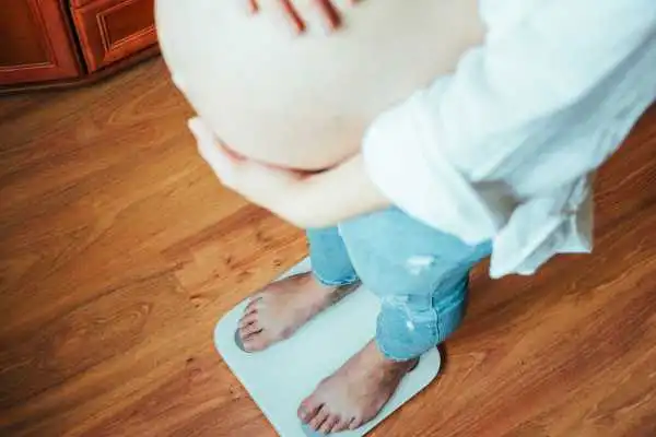 Image of woman weighing herself and experiencing weight gain through pregnancy Malvern Wells
